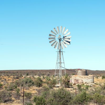 A windmill, water tank and electricity pylon on road N12 between Beaufort West and Klaarstroom in the Western Cape Karoo